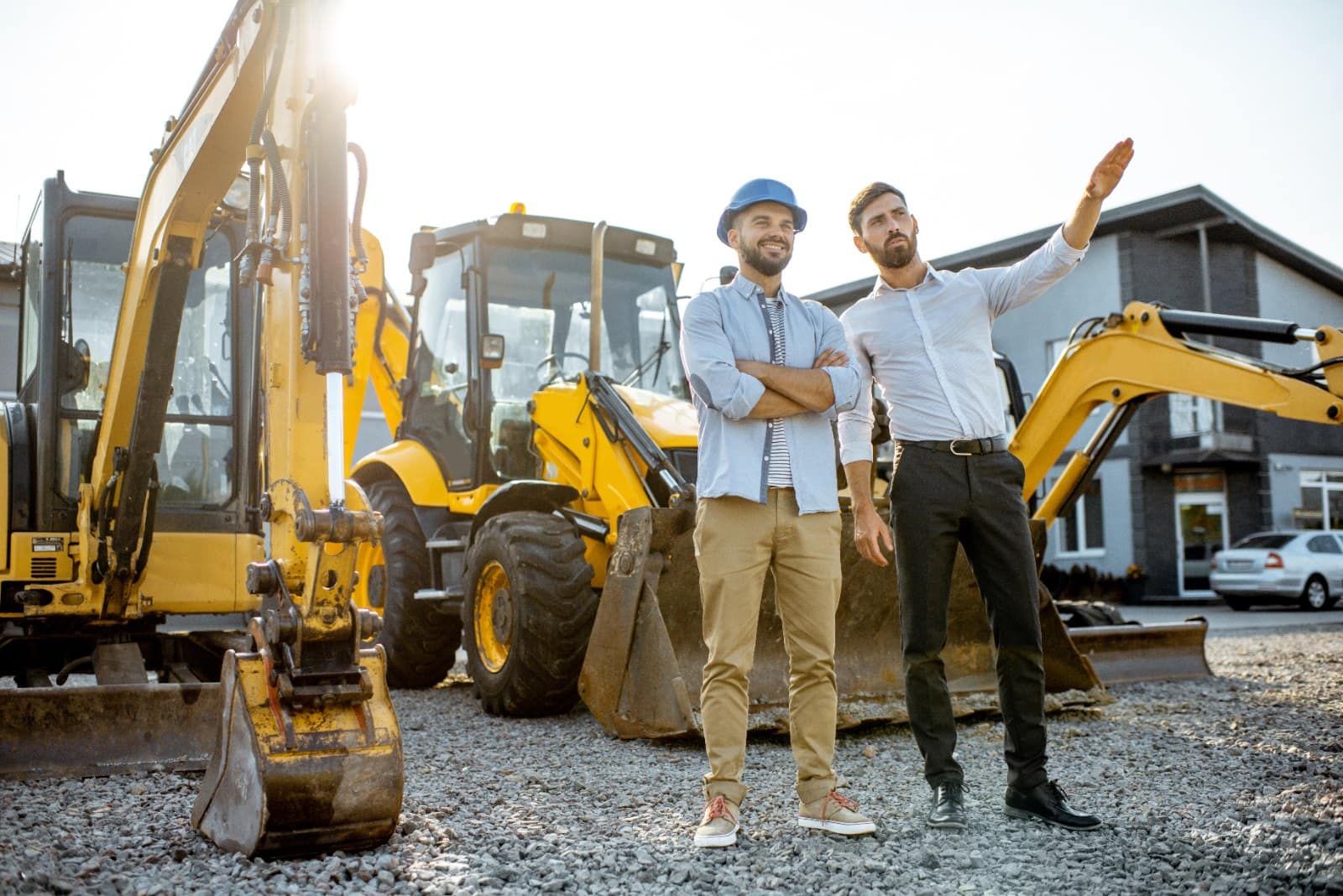 Business owner and dealer consultant beside excavators at an equipment dealership