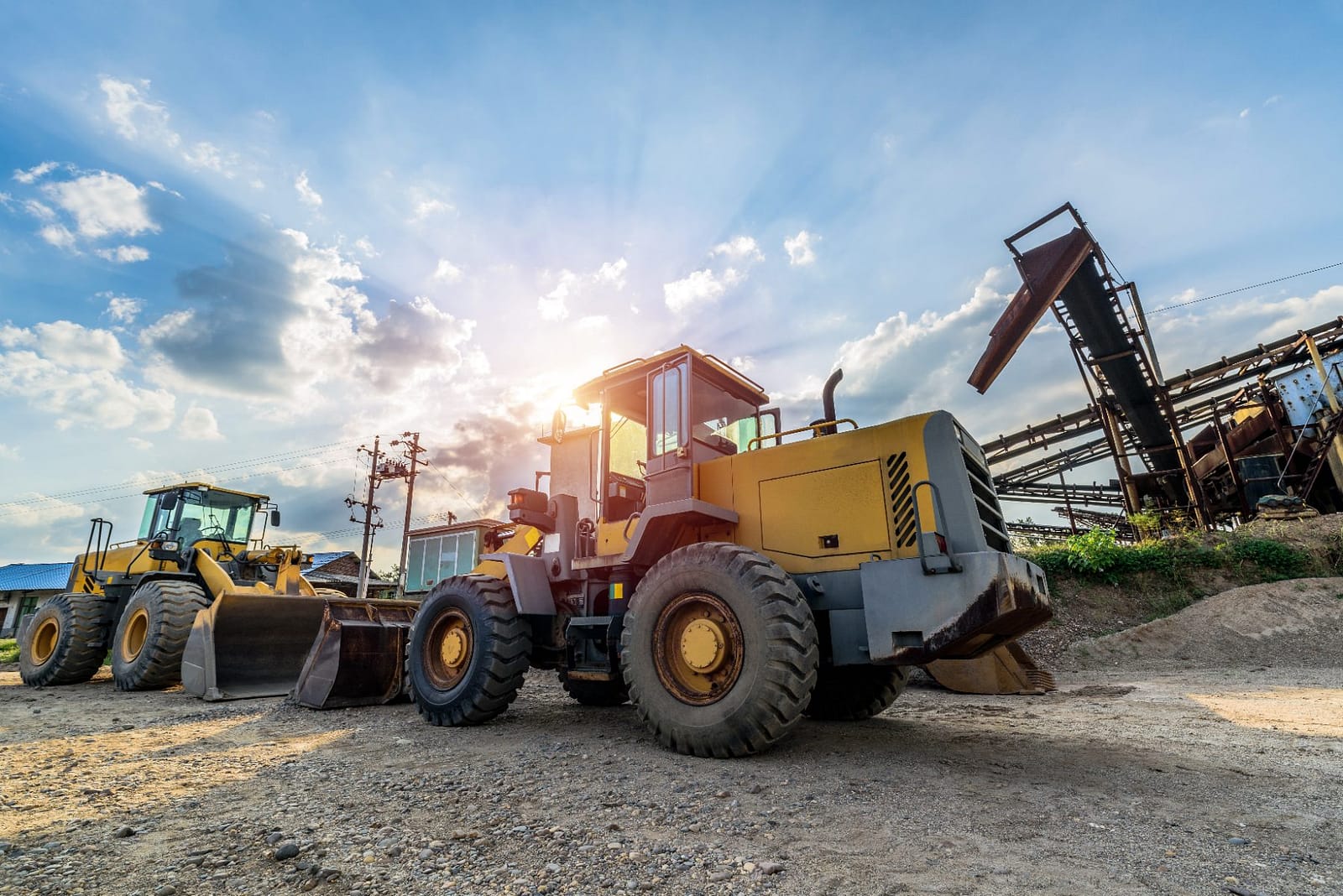 Wheel loaders working on a construction site at sunset